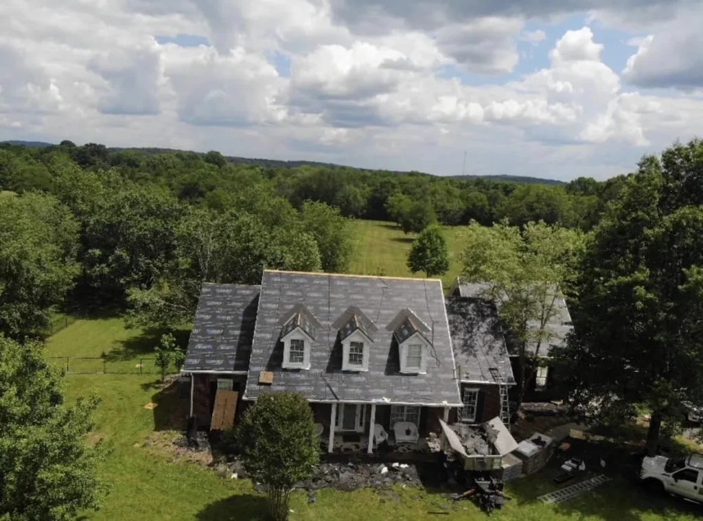 Drone view of a crew tearing off an old roof on a house with three dormers