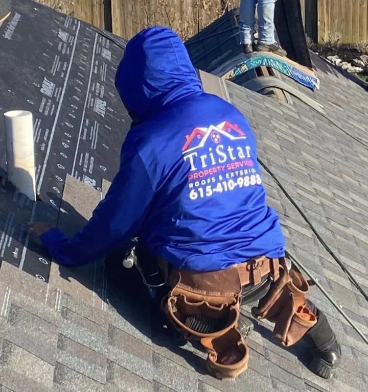 A TriStar roofer in a branded hoodie rolling out underlayment